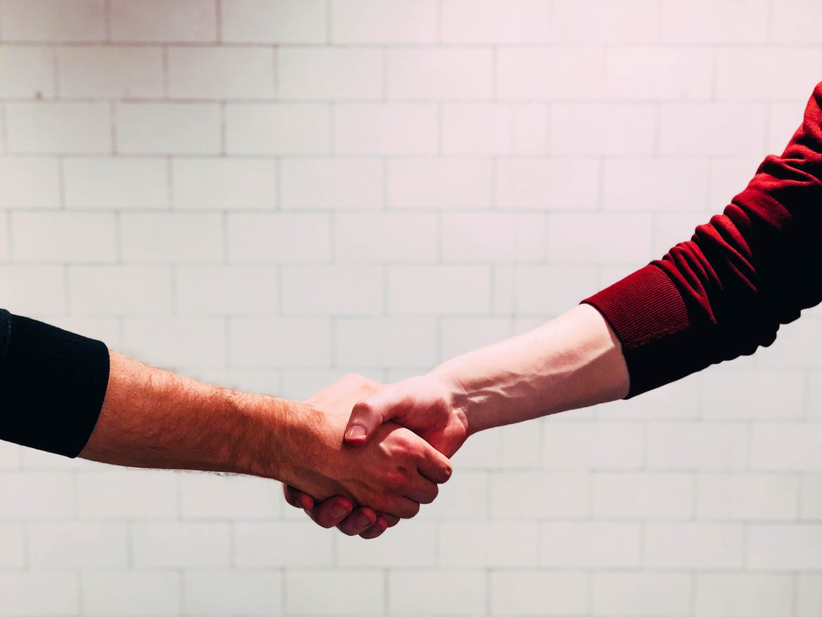 Illustration of handshake with caution symbols, representing the risks of informal agreements, featuring TMBTQ Law and highlighting their legal services on the website.